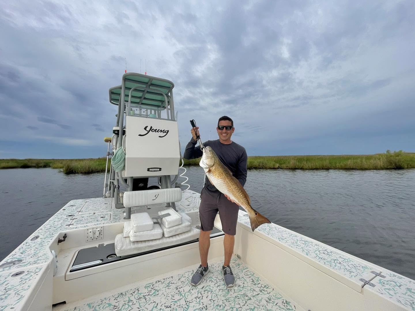 Angler holding a redfish on a bay boat in the Barataria marsh